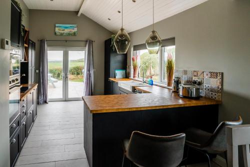 a kitchen with a counter and some chairs in it at Holmestead Cottage in Tyrella