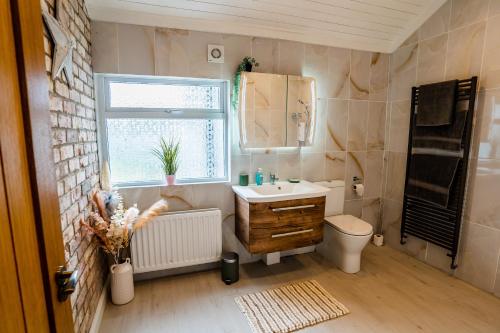een badkamer met een wastafel, een toilet en een raam bij Holmestead Cottage 