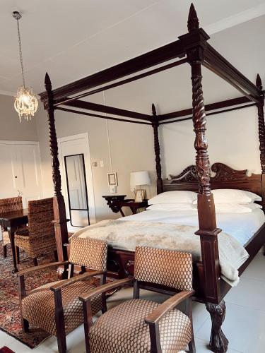 1 dormitorio con cama con dosel, sillas y mesa en Ebony Moon en Mthatha