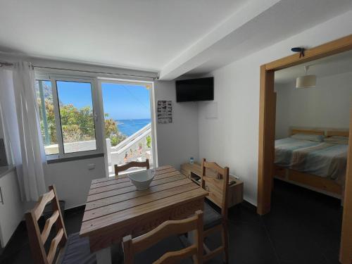 ein Zimmer mit einem Tisch und einem Bett und einem Fenster in der Unterkunft maktub sunset cottage in Paul do Mar