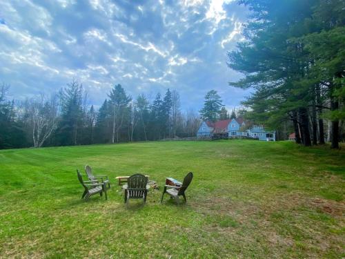 three chairs and a table in a field at WOW New Spectacular Franconia Home - history - views - fire pit - hot tub - pool - grandeur - MUST SEE in Franconia