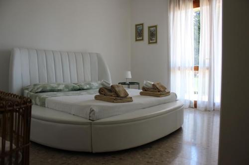 a bedroom with a large white bed with shoes on it at APPARTAMENTO AMPIO E LUMINOSO LAGO D'ORTA in San Maurizio dʼOpaglio