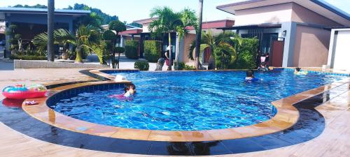 a pool with people swimming in it in a resort at สวนหินวิลล่า รีสอร์ท in Ban Chot