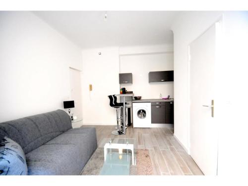 uma sala de estar com um sofá cinzento e uma mesa em Superbe studio meublé cosy avec patio au calme Jean médecin em Nice