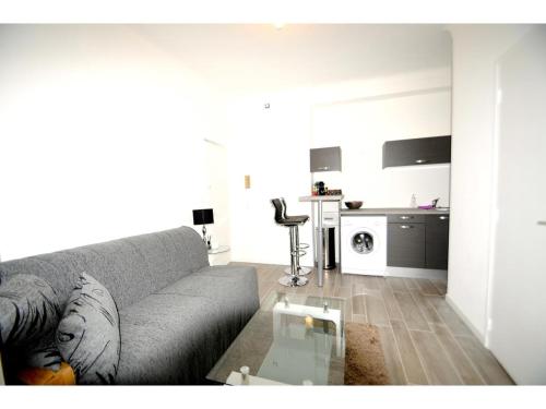 uma sala de estar com um sofá e uma mesa de vidro em Superbe studio meublé cosy avec patio au calme Jean médecin em Nice