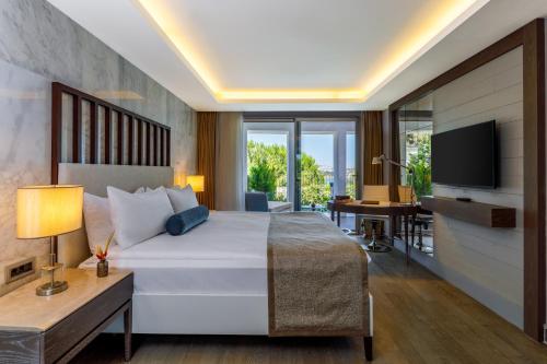 a bedroom with a large white bed and a television at Sirene Luxury Hotel Bodrum in Yalıkavak