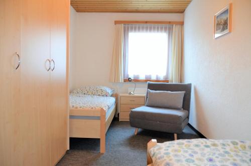 a bedroom with a bed and a chair and a window at Chasa Arlu in Samnaun