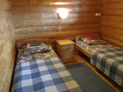 two beds in a room with wooden walls at Lappalaisen lomamökit Lepola in Puumala