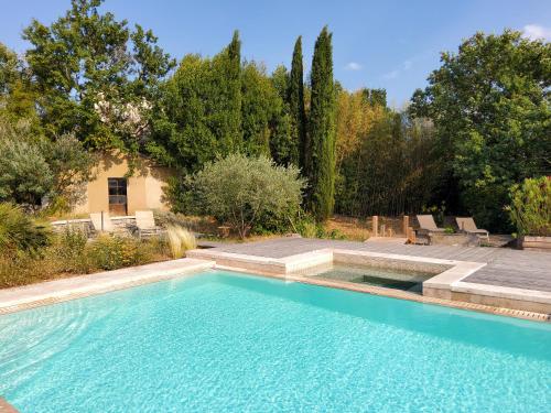 a swimming pool in a yard with chairs and trees at Les Carriers "maison d'hôtes" in Vogüé