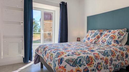 um quarto com uma cama com um edredão colorido e uma janela em Le petit Moulin de la Motte em Bellenot-sous-Pouilly