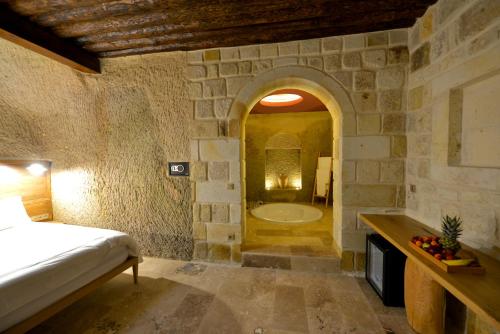 a bedroom with a bed and a tub in a room at Evanthia Cave Suites in Ürgüp