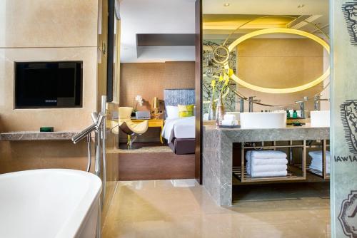 a bathroom with a bed and a sink and a tub at Sofitel Zhengzhou International in Zhengzhou