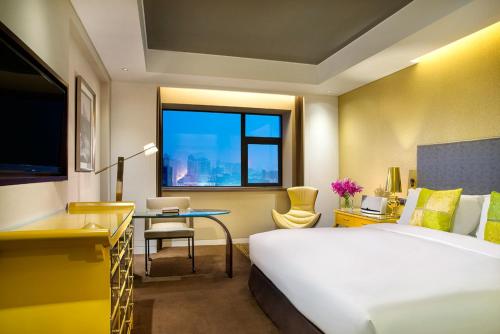 a hotel room with a bed and a desk and a window at Sofitel Zhengzhou International in Zhengzhou
