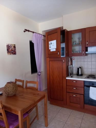 a kitchen with wooden cabinets and a wooden table with a wooden table at Flisvos Apartments in Megalochori