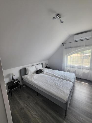 a white bedroom with a bed and a window at Tiszavirág Üdülőház in Kisköre