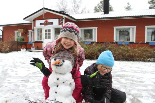 two children playing with a snowman in the snow at Loma-Rantala Cottages in Tahkovuori