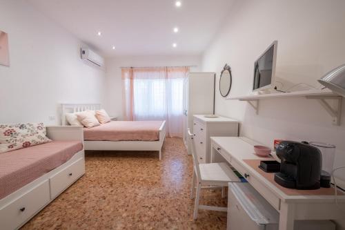 a bedroom with two beds and a desk and a television at Casa Rosa Beige e Blu in Rome