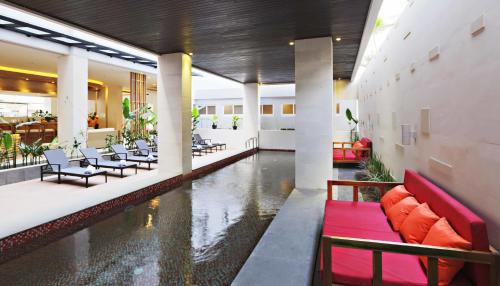 a lobby with a pool of water with chairs and tables at Euphoria Hotel in Legian