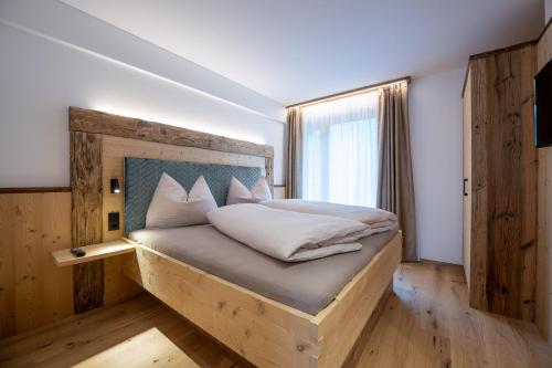 a bedroom with a bed with a wooden headboard and a window at Ladinser Hof Western Suite in Castelrotto