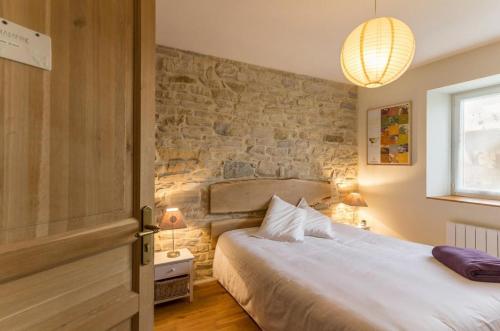 une chambre avec un lit et un mur de briques dans l'établissement La Maison au Comptoir, à Aiserey