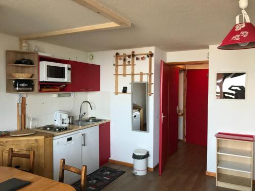 une cuisine avec des placards rouges et une porte rouge dans l'établissement Studio chaleureux à Vallandry, 4 pers., proche pistes et commerces, animaux admis - FR-1-411-359, à Landry