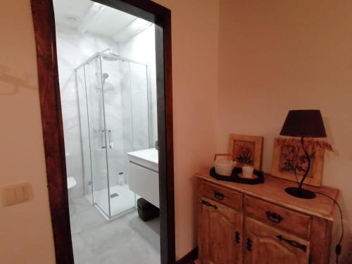 a bathroom with a shower and a wooden dresser at Gerês - Refúgio das Laranjeiras in Geres