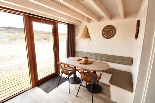 een kleine eetkamer met een tafel en stoelen bij Breezand Beachhouses in Vrouwenpolder