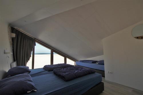 two beds in a room with a large window at Breezand Beachhouses in Vrouwenpolder