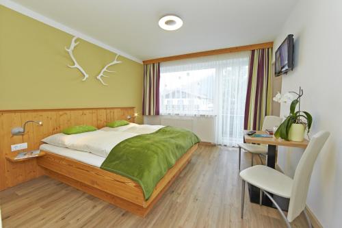 een slaapkamer met een bed, een bureau en een stoel bij Hotel Garni Landhaus Gitti in Zell am See