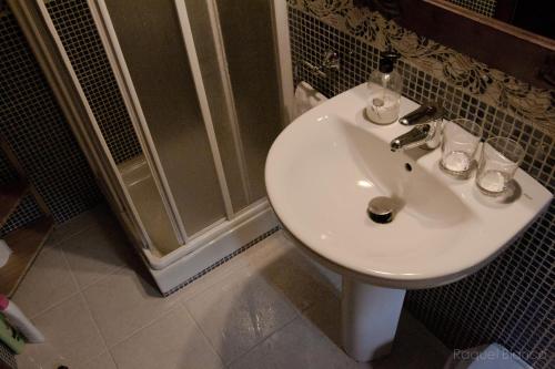 La salle de bains est pourvue d'un lavabo blanc et d'une douche. dans l'établissement Hotel Saueth, à Tredós