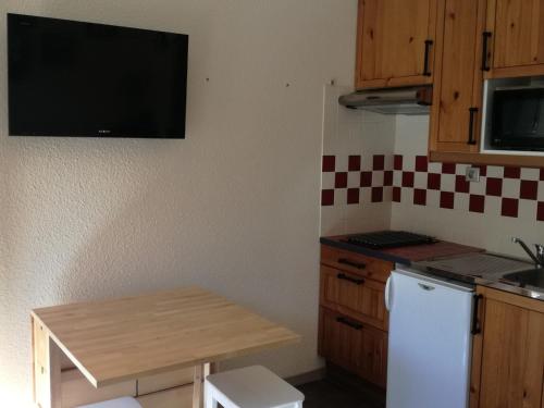 Il comprend une petite cuisine avec une petite table et un réfrigérateur. dans l'établissement Studio cabine cosy au pied des pistes avec balcon - FR-1-557-115, à Les Adrets