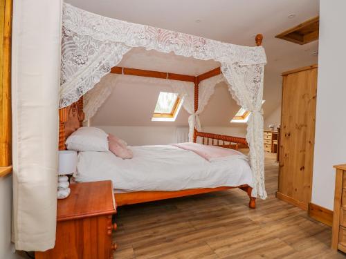 1 dormitorio con cama con dosel y cortinas blancas en Little Lodge, en Kings Lynn