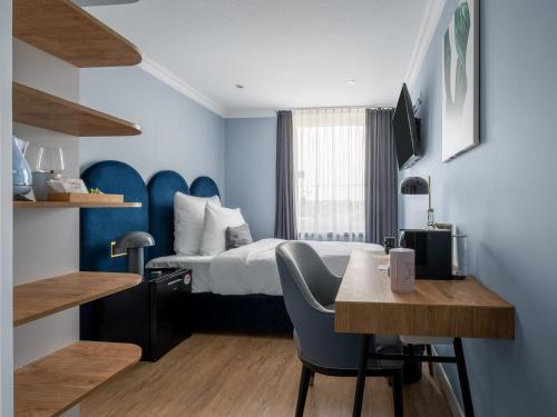 Habitación de hotel con cama, escritorio y mesa. en numa I Artol Rooms & Apartments en Düsseldorf