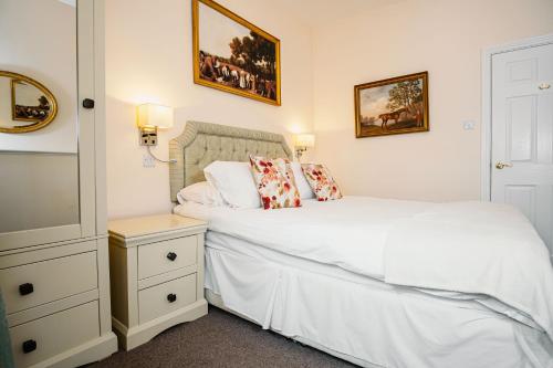 a bedroom with a white bed and a nightstand and two beds at The Town House in Douglas