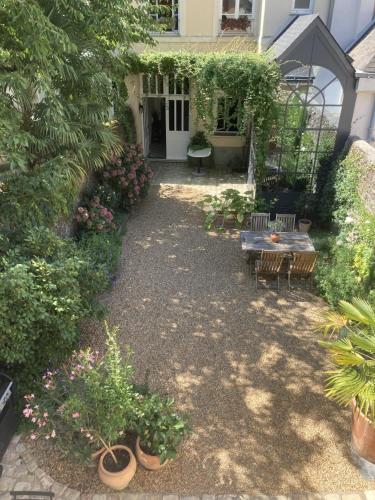 un jardin avec une table, des bancs et des plantes dans l'établissement La Maison du Cocher - Chambre indépendante climatisée en Hypercentre - Lit Queen Size, à Angers