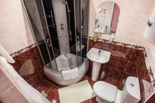 y baño con ducha, aseo y lavamanos. en Hotel Benefit, en Perm