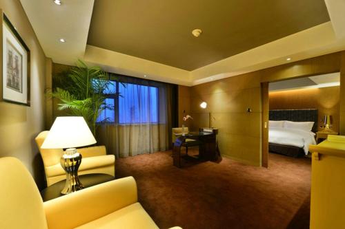 a hotel room with a bed and a couch and a lamp at Sofitel Zhengzhou International in Zhengzhou