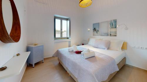 a white bedroom with a bed and a sink at ONAR RESIDENCE PAROS in Chrissi Akti