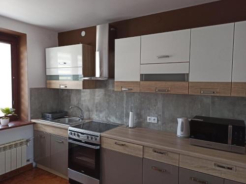 a kitchen with white cabinets and a stove top oven at Rodzinne Zacisze Bysina in Bysina