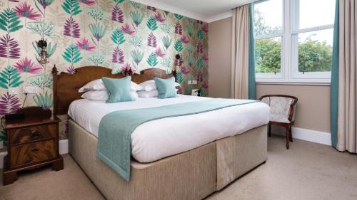 a bedroom with a large bed with floral wallpaper at Sunbank House Metro Hotel in Perth