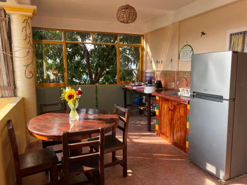 a kitchen with a wooden table and a refrigerator at Ananda Guest House Yoga & Meditación in Puerto Escondido