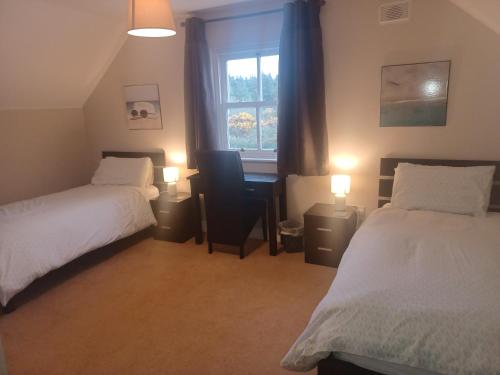 a bedroom with two beds and a desk and a window at No 9 Seanachaí Holiday Homes Holiday home in Dungarvan