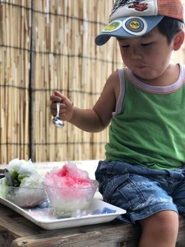 a little boy sitting on a table eating food with a spoon at Doublerainbow Resort Katsuura in Katsuura
