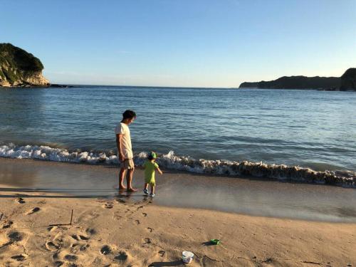a man and a child standing on the beach at Doublerainbow Resort Katsuura in Katsuura