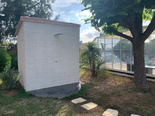 un bâtiment blanc à côté d'un arbre et d'une maison en verre dans l'établissement L'APARTE - Studio Les AMANDIERS, à Pignans