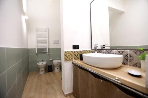 een badkamer met een witte wastafel en een spiegel bij La Casetta delle Scienze Suite in Palermo