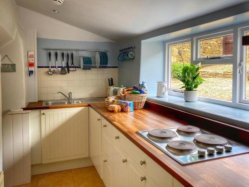 a kitchen with a counter and a stove top oven at Baker's Cottage in Castle Combe