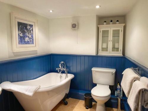 a bathroom with a white tub and a toilet at Baker's Cottage in Castle Combe