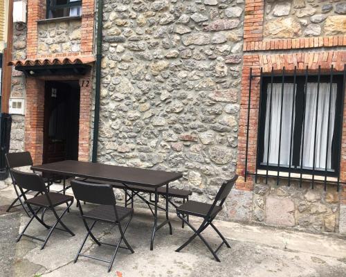 una mesa y sillas frente a un edificio de piedra en ApartamentosArturo CasaRural Pancarale-Llanes, en Llanes