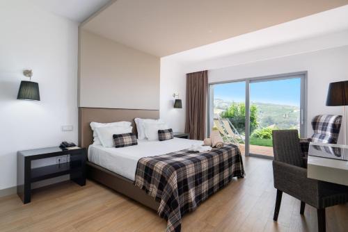 Delfim Douro Hotel في لاميغو: غرفة نوم بسرير ومكتب ونافذة